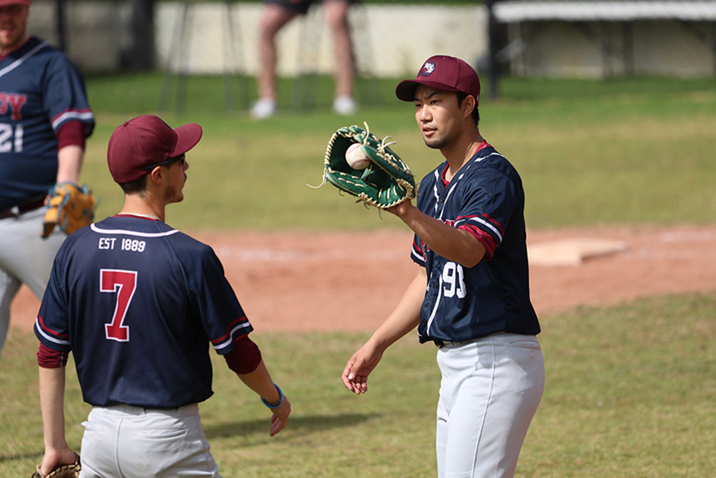 球を受ける金井投手とチームメイト